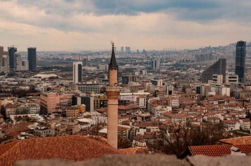 Free Panoramic view of Ankara's cityscape with modern skyscrapers and historic minaret under cloudy skies. Stock Photo