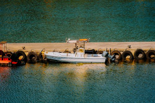 Free Aerial view of a motorboat moored along a pier, reflecting tranquil waters. Stock Photo