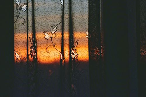 Free Elegant curtains reveal a vivid sunset, creating a dramatic and artistic ambiance. Stock Photo