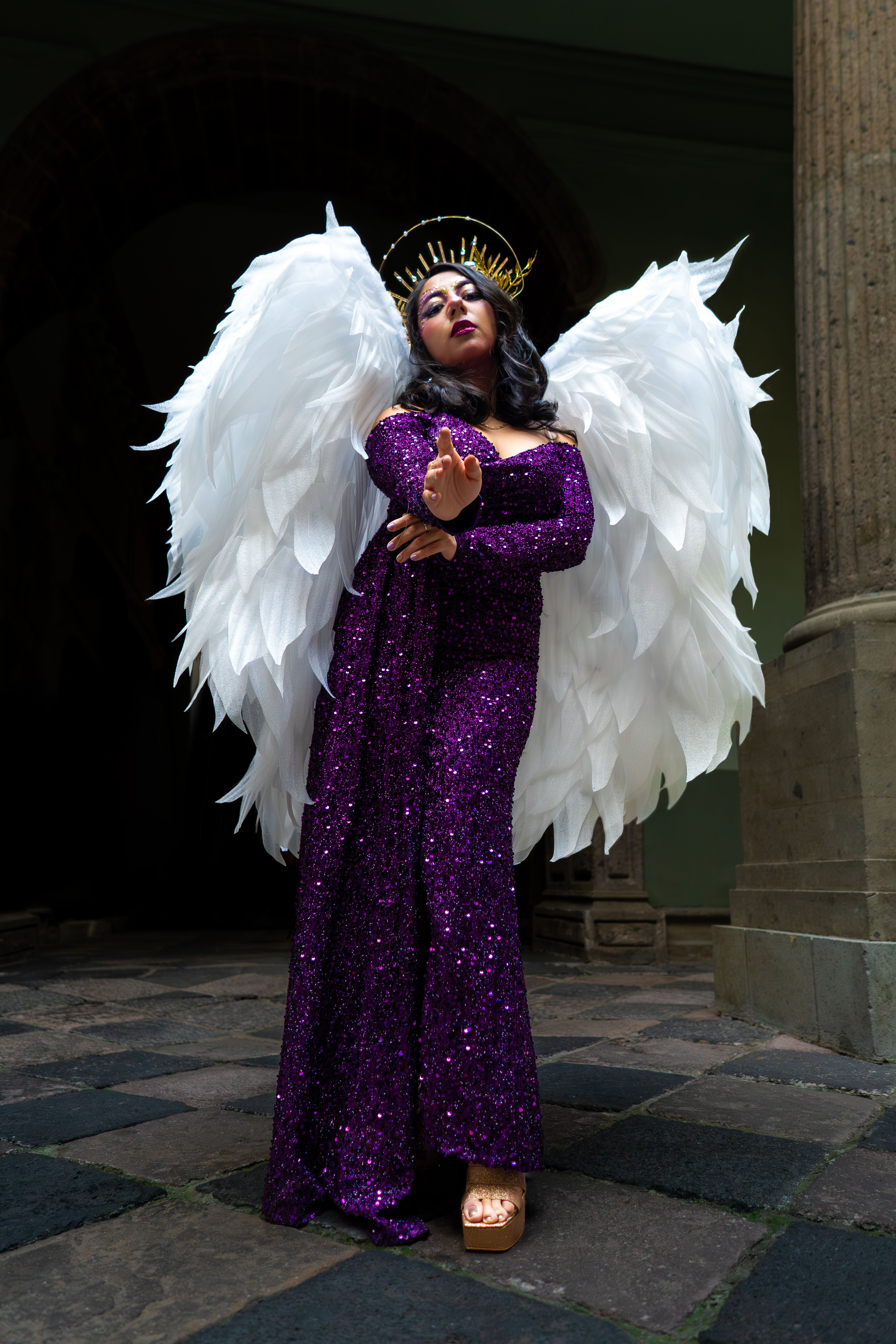 Striking portrait of a woman in angel wings and glittering dress in an elegant pose, captured in Mexico City.