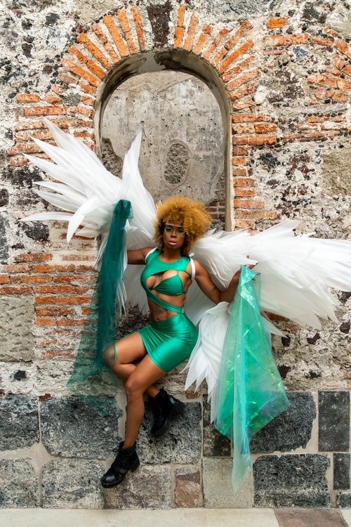 Free Woman in angel costume poses against historic wall, Mexico City. Stock Photo