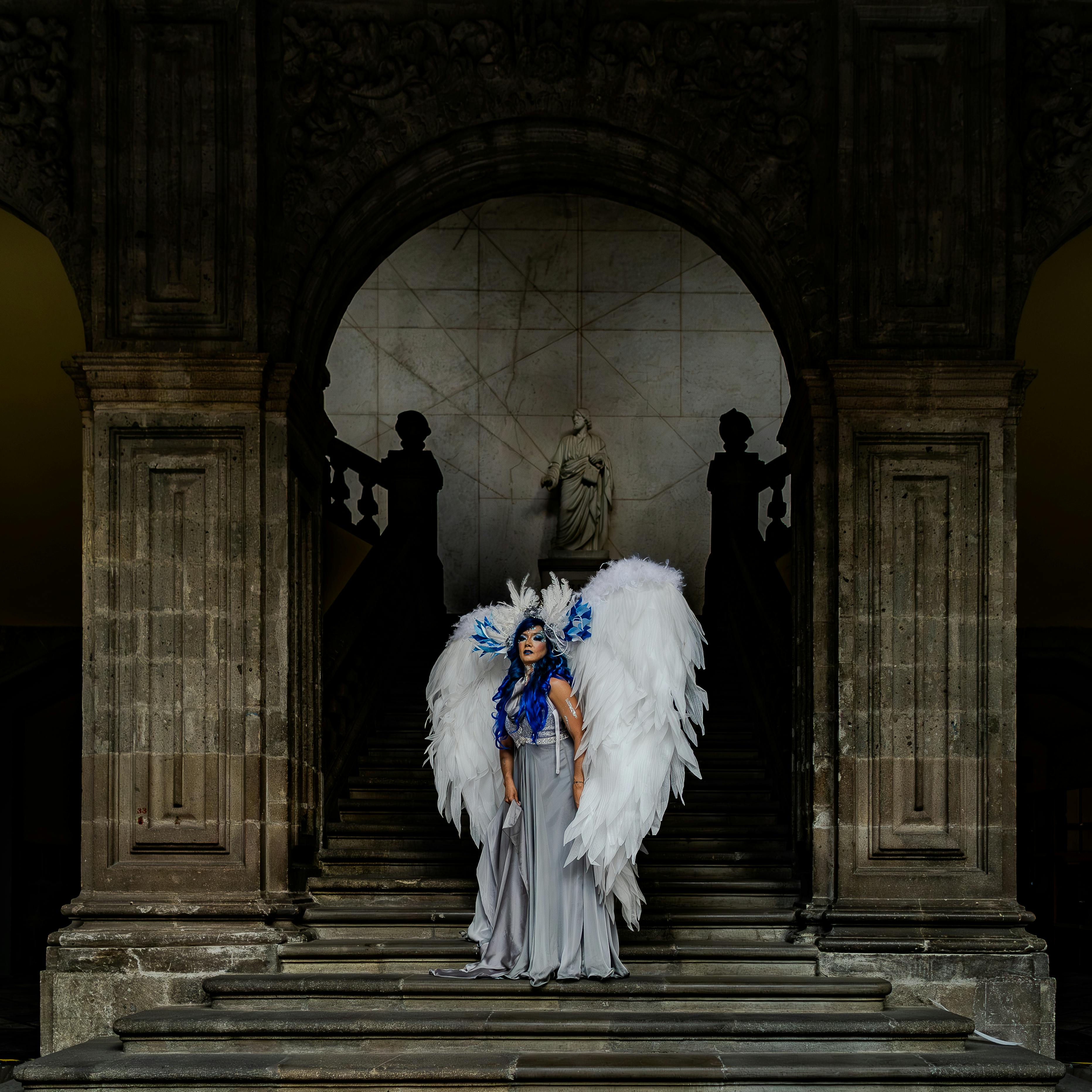 A striking figure dressed as an angel on historic steps in Ciudad de México, exuding grace and elegance.