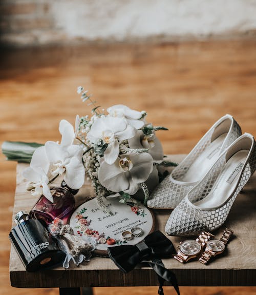 Wedding Rings by Flowers and Shoes on Small Table