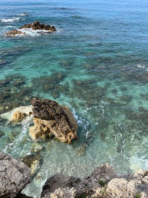 Free A serene view of clear ocean water gently crashing against rugged rocks, perfect coastal scenery. Stock Photo