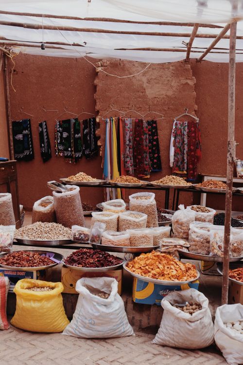 Free Colorful market stall displaying a variety of dried foods and textiles, creating a lively shopping atmosphere. Stock Photo