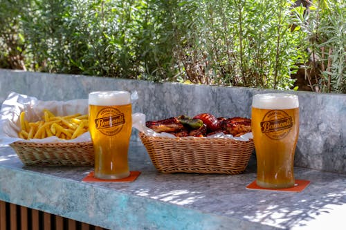 Two beer glasses and a basket of fries on a table