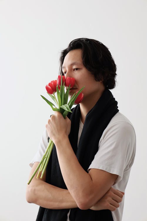 Man Holding and Smelling a Bouquet of Flowers 