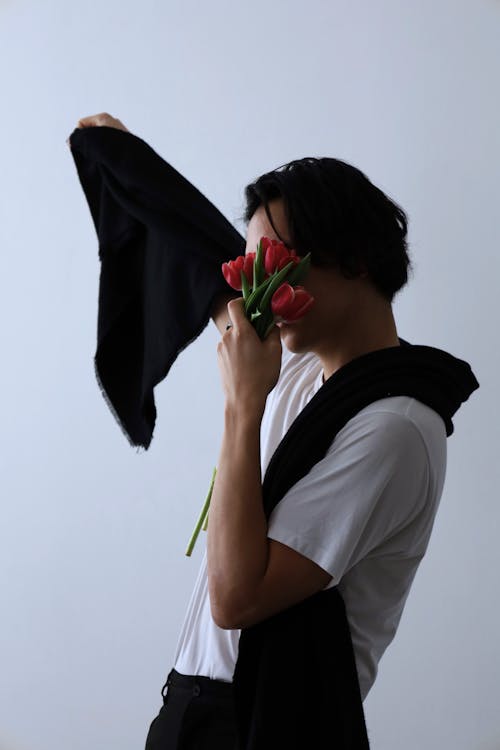 Studio Shot of a Man in a Simple Outfit Holding Flowers