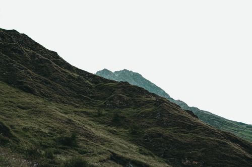 Free Capture of a rugged mountain range under an overcast sky with lush green grass, ideal for travel and nature themes. Stock Photo