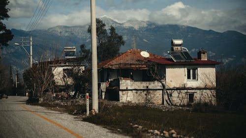 A house on the side of the road with a mountain in the background