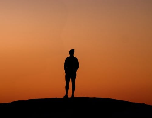 A silhouette of a person standing on a hill