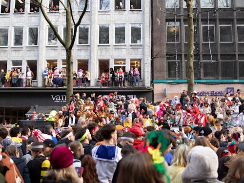 A crowd of people in costumes and masks on a street