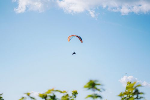 Free A paraglider gracefully flies across a clear blue sky, epitomizing adventure and freedom. Stock Photo