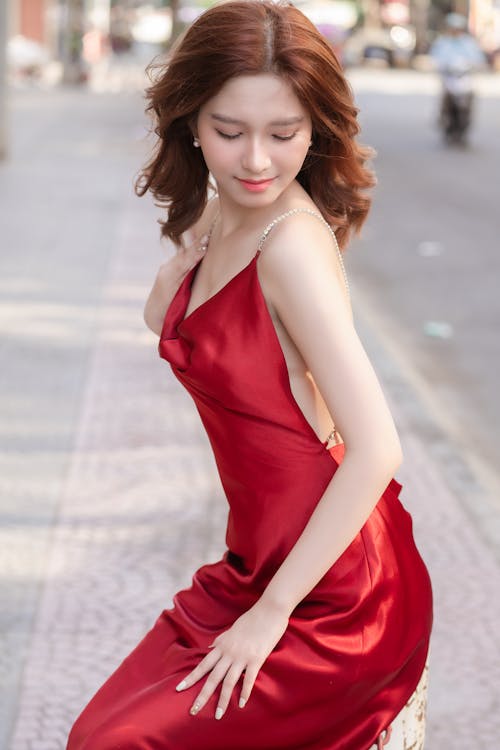 A woman in a red dress posing on the street