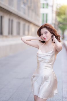 Young woman in silk dress posing confidently on an urban city street. Fashionable and elegant look.