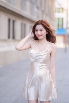 Chic woman in a silk dress posing on a city street, exuding modern elegance.