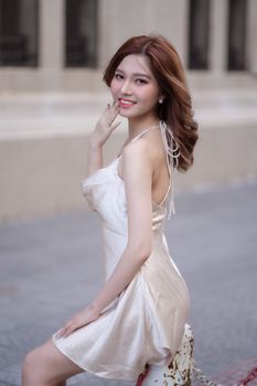 Stylish young woman in a silk dress posing confidently in a city environment, radiating elegance and charm.