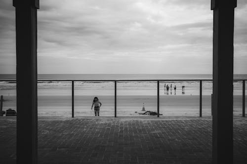 A black and white photo of people walking on the beach