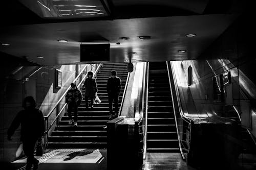 Black and white photo of people walking up an escalator