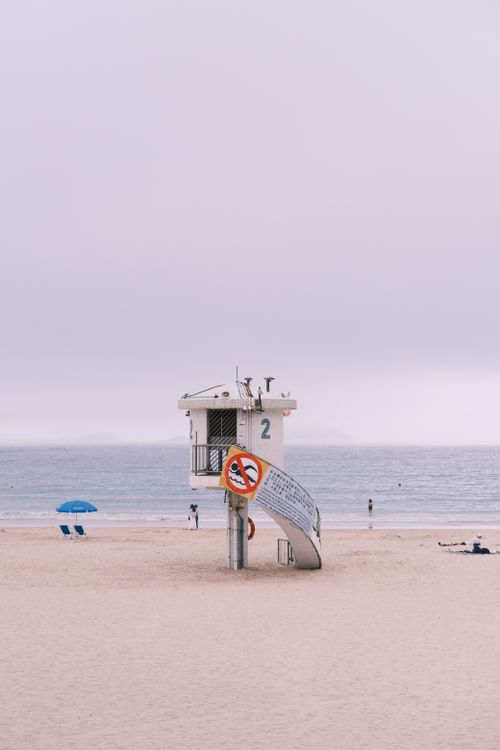 Free A lifeguard tower on a serene sandy beach under a cloudy sky, perfect for stock imagery. Stock Photo