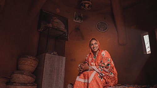 Smiling Woman in Traditional Clothing Sitting in House