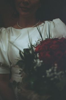 A beautifully captured moment of a bride holding a red rose bouquet, showcasing elegance and intimacy.