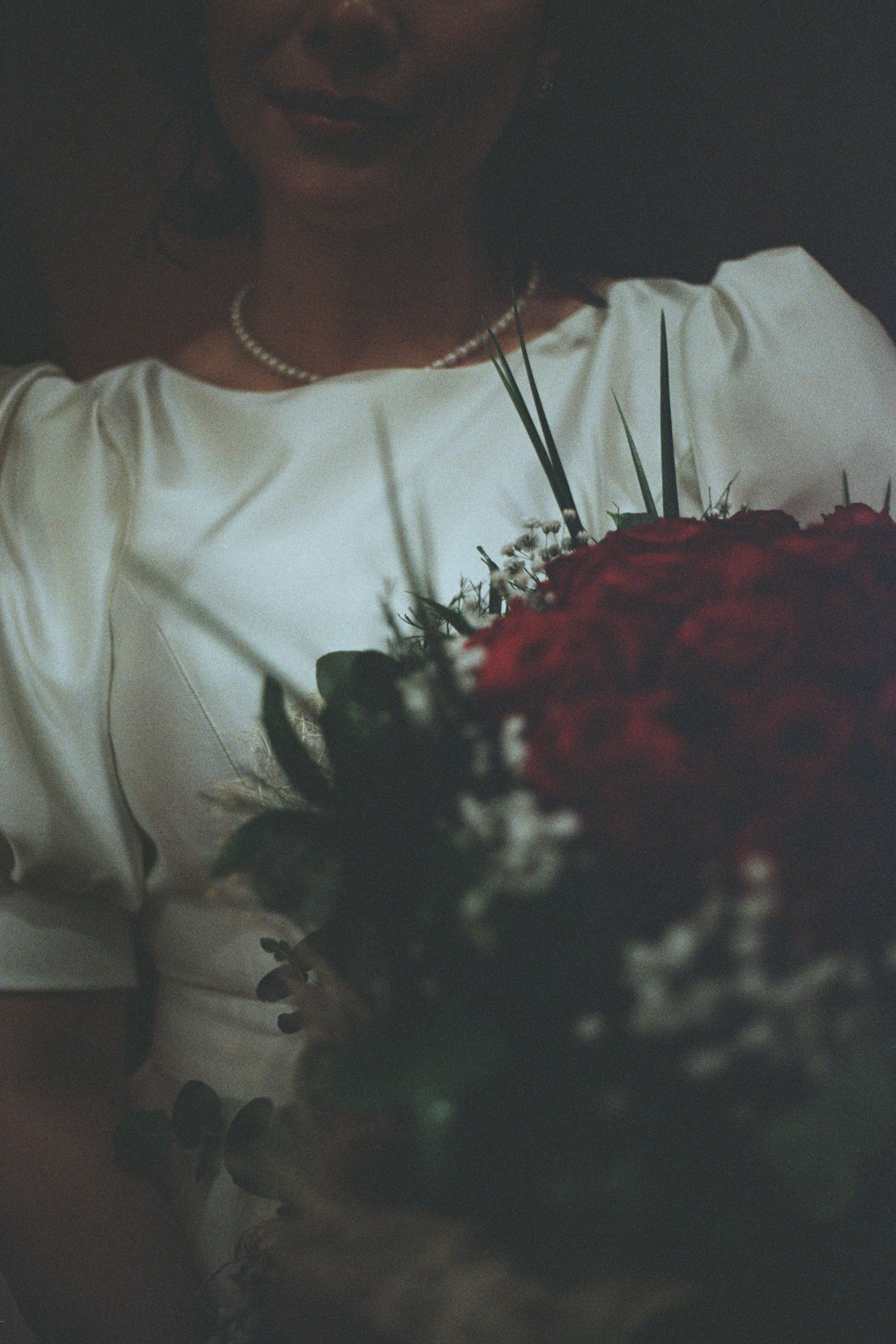 Dark Photo of a Bride Holding Bouquet of Red Roses · Free Stock Photo
