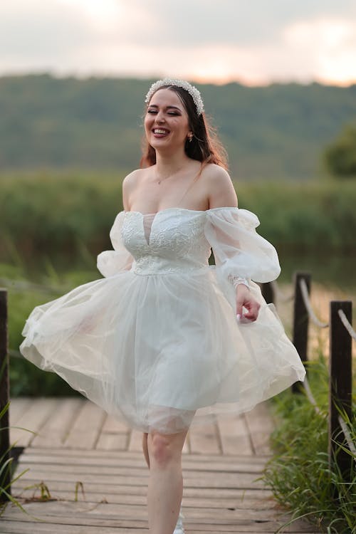 A woman in a white dress is walking on a dock