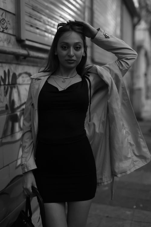 Free Stylish woman poses in an urban street setting wearing a chic outfit, captured in black and white. Stock Photo