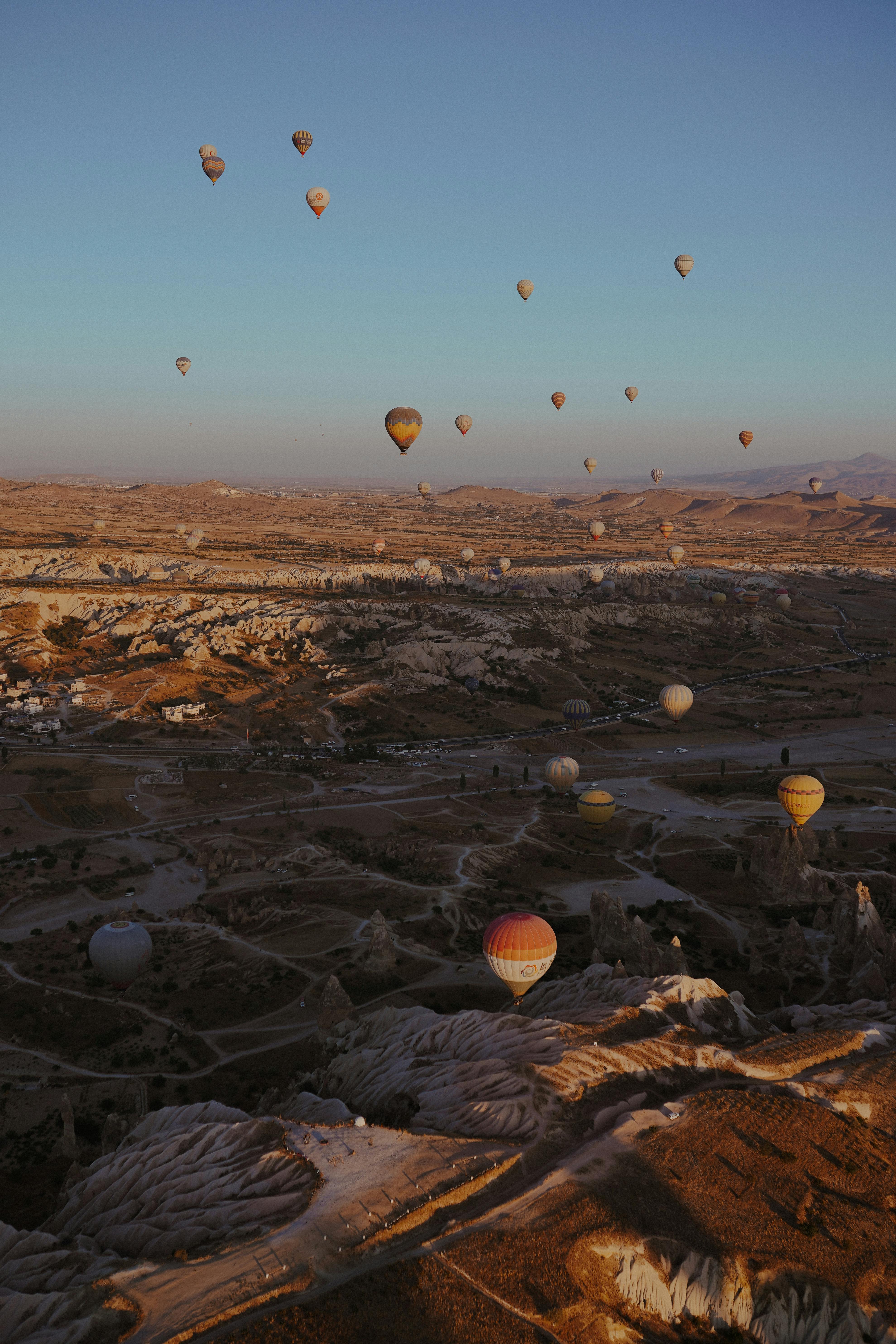Stunning aerial view of hot air balloons floating above Cappadocia's unique landscape at sunrise.