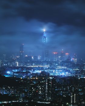 A dramatic night view of Taipei's skyline with mist and glowing skyscrapers, including the iconic Taipei 101.