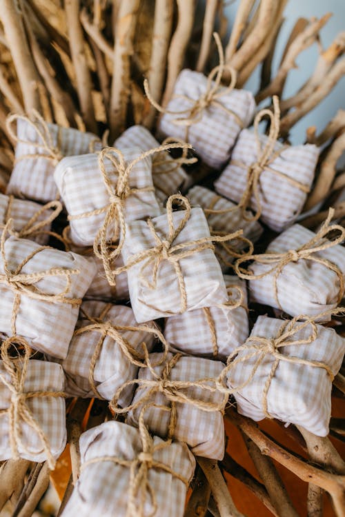 Collection of small, rustic gift packages tied with twine on a bed of twigs.