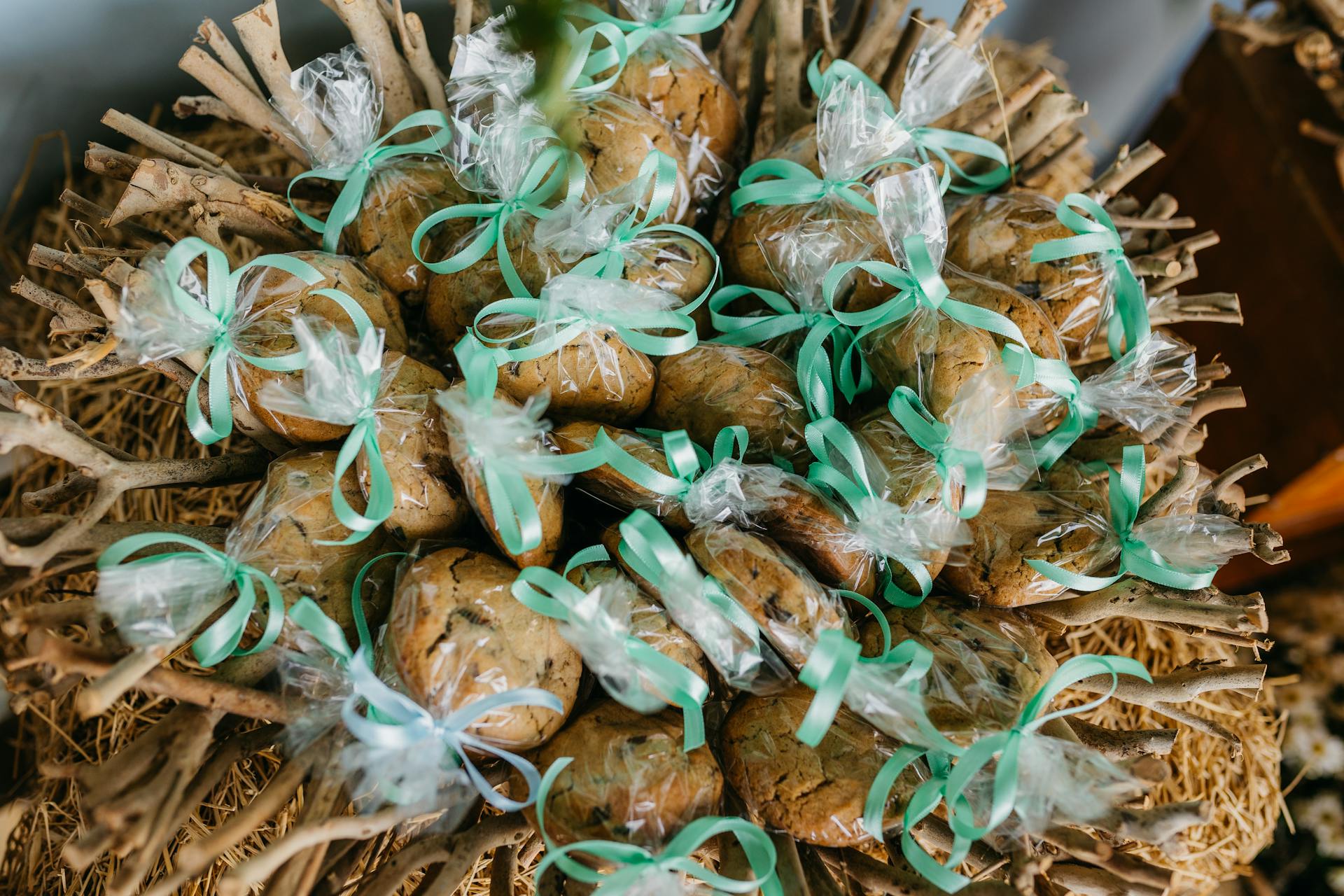 Beautifully wrapped cookies on rustic sticks accented with green ribbons, perfect for gifts.