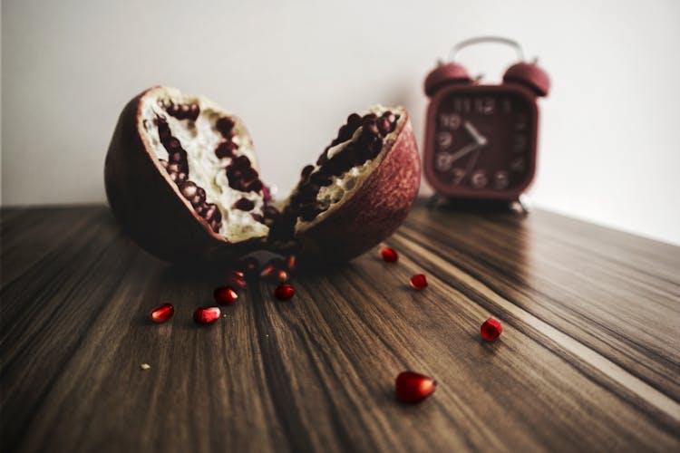 Red And White Round Fruit On Brown Wooden Table With Red Alarm Clock