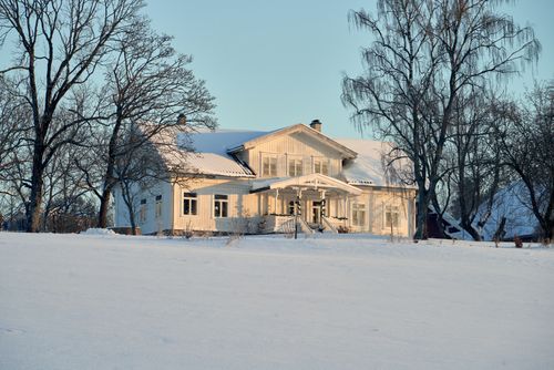 Free Charming Scandinavian farmhouse with snow-covered landscape and bare trees, showcasing a winter scene. Stock Photo