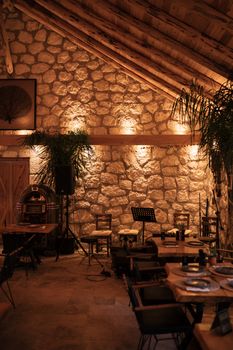 Warm and inviting rustic restaurant interior with lit stone walls and wooden accents.