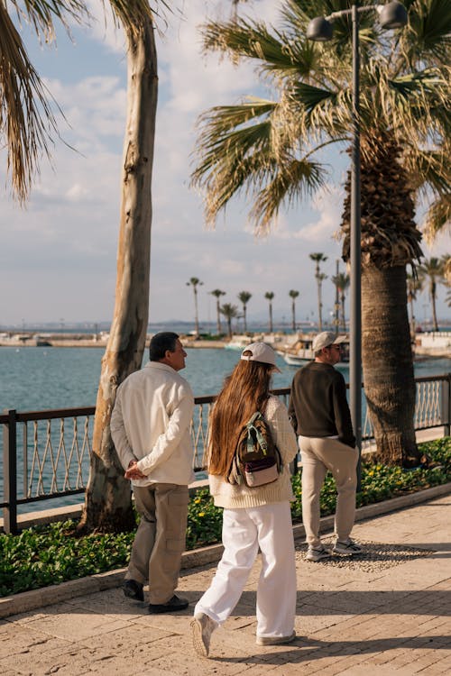 Two people walking along the waterfront near palm trees