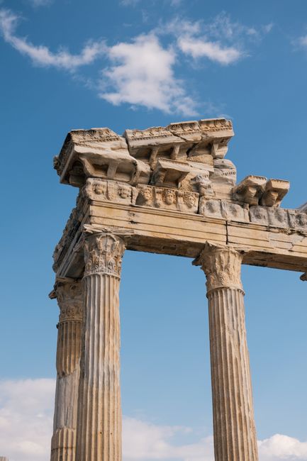 Close-up of ancient Greek columns under a bright blue sky, showcasing historical architecture.