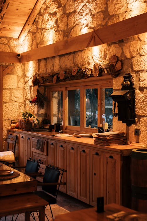 A kitchen with stone walls and wood cabinets
