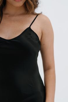Close-up portrait of a woman in a black silk dress, showcasing fashion elegance.
