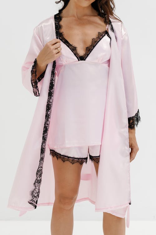 Free Stylish pink satin lingerie set with lace details showcased in a studio photoshoot. Stock Photo