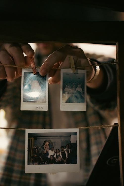 A person holding up polaroids with pictures of people