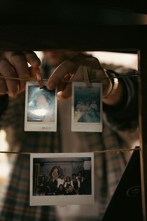 Free Hands pinning vintage Polaroid photos on a string, creating a nostalgic feel. Stock Photo