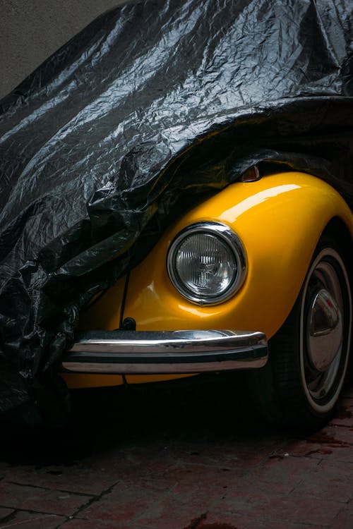 A yellow beetle covered in a black tarp