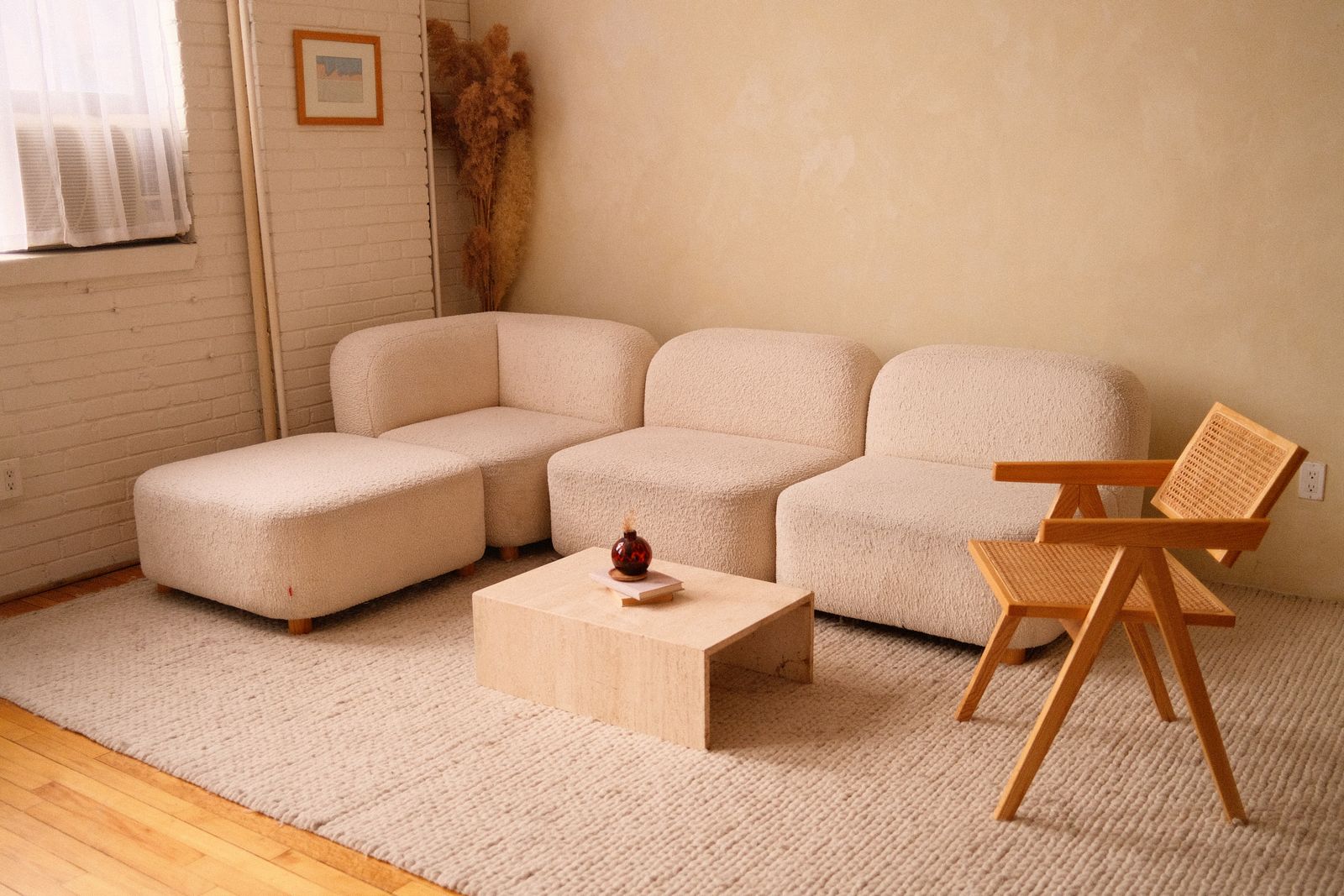 A plaster-toned living room with a bouclé sectional and a travertine table — photo by Wendy Wei on Pexels