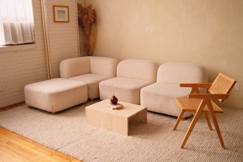 Free A cozy minimalist living room featuring a plush sofa and contemporary wooden chair. Stock Photo