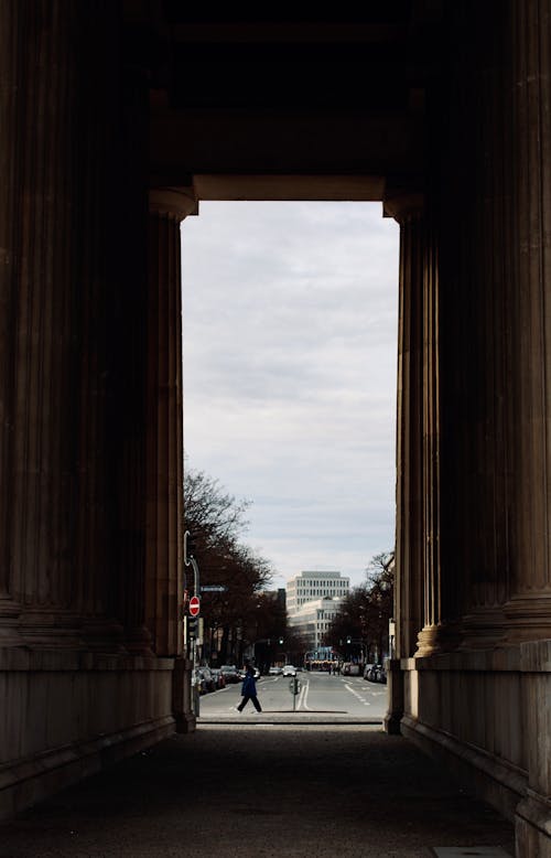 A person walking down a street through an archway
