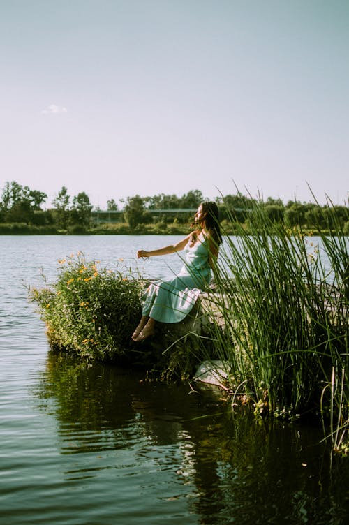 Woman Wearing Dress Sitting by the Lake 