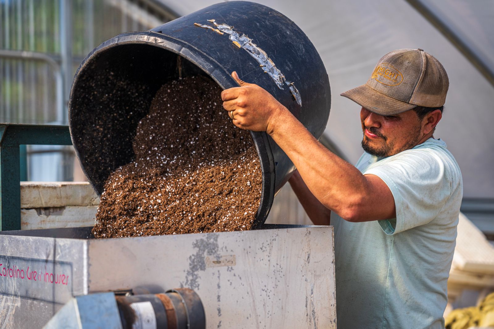 Worker handling soil with a bucket in an outdoor work area