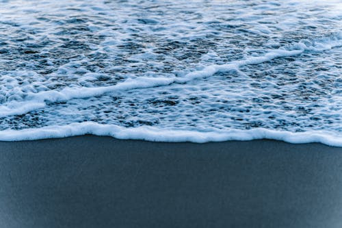 Close-up of a Foamy Wave Washing Up the Beach